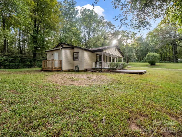 a white house with a big yard and large trees