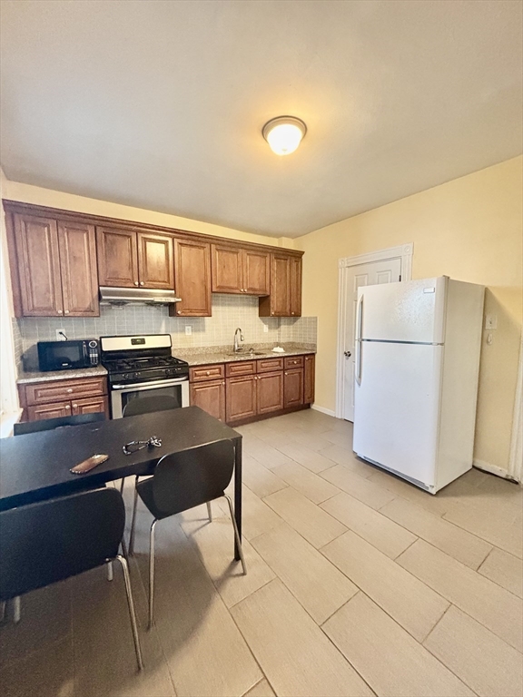 11 Raven Street, Unit 2 Boston, MA 02125 - Photo 1 of 10 a kitchen with a sink a stove a refrigerator cabinets and a dining table
