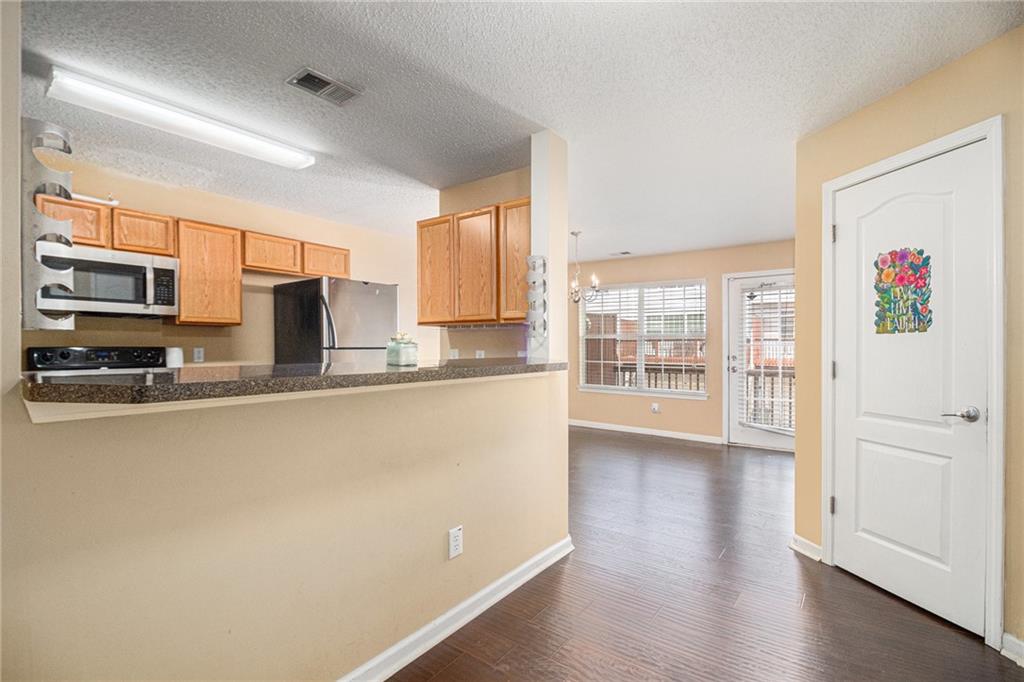 3262 Cascade Parc Boulevard Southwest Atlanta, GA 30311 - Photo 7 of 24 a large kitchen with stainless steel appliances a large counter top a stove and a refrigerator with wooden floor