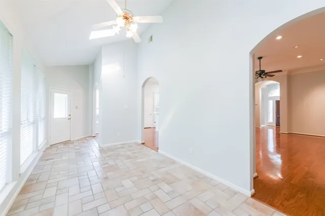 an empty room with wooden floor windows and entrance
