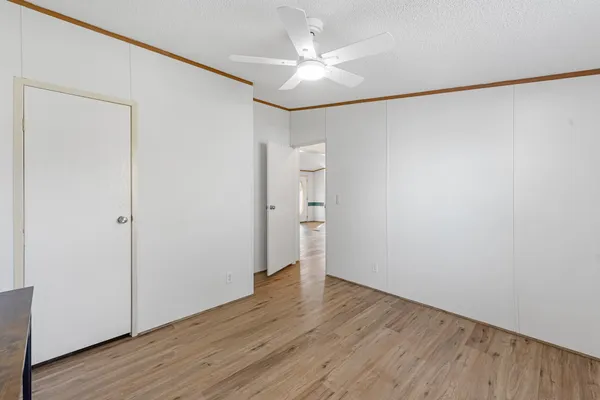 an empty room with wooden floor and a ceiling fan