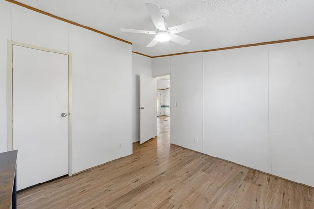 an empty room with wooden floor and a ceiling fan