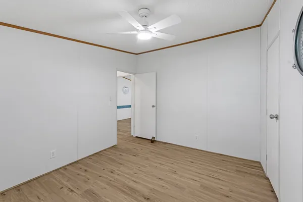 an empty room with wooden floor and a ceiling fan