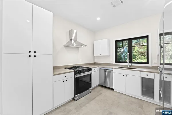 a kitchen with stainless steel appliances granite countertop white cabinets and window