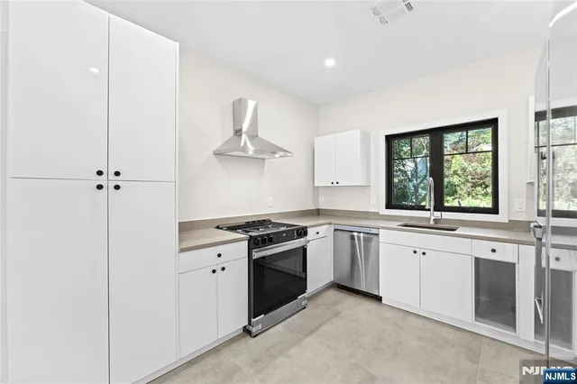 a kitchen with stainless steel appliances granite countertop white cabinets and window