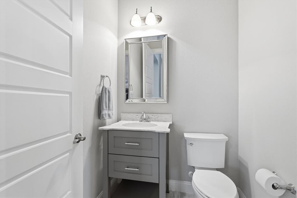 8713 Homestead Boulevard Rowlett, TX 75089 - Photo 17 of 28 a bathroom with a toilet sink vanity and mirror