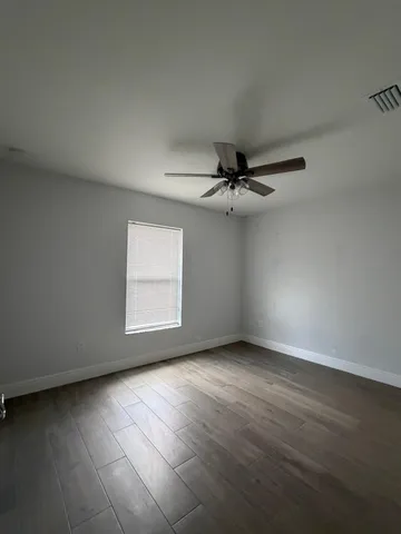 an empty room with a window and a ceiling fan