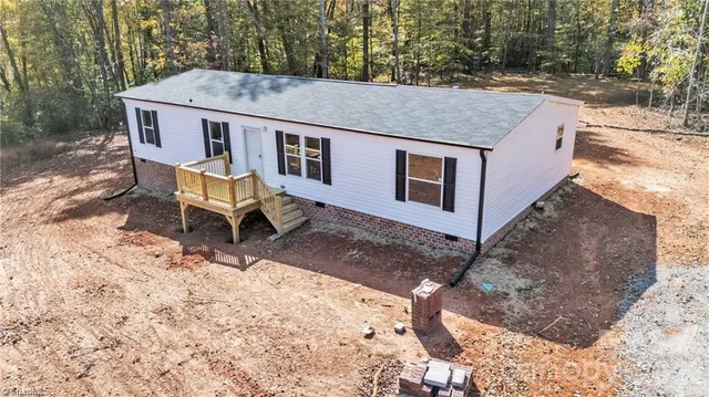 a aerial view of a house with a yard covered in the forest