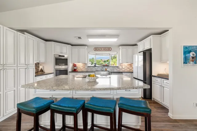 a kitchen with granite countertop a table chairs microwave and refrigerator