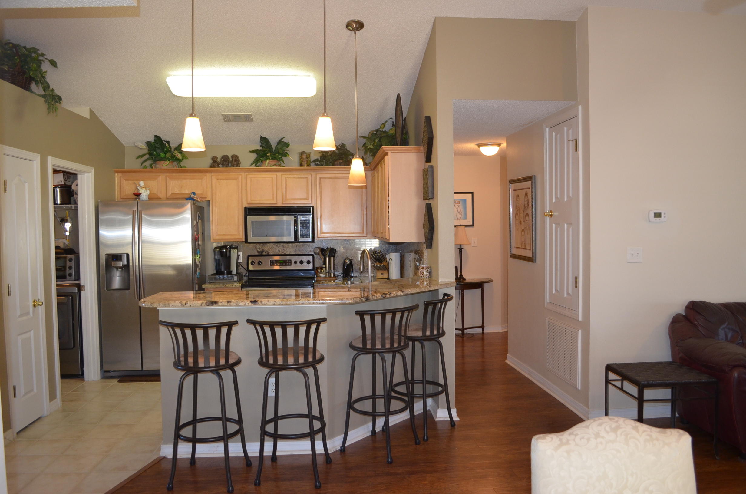669 East Shipwreck Road Santa Rosa Beach, FL 32459 - Photo 13 of 35 a kitchen with stainless steel appliances kitchen island granite countertop a dining table chairs and a refrigerator