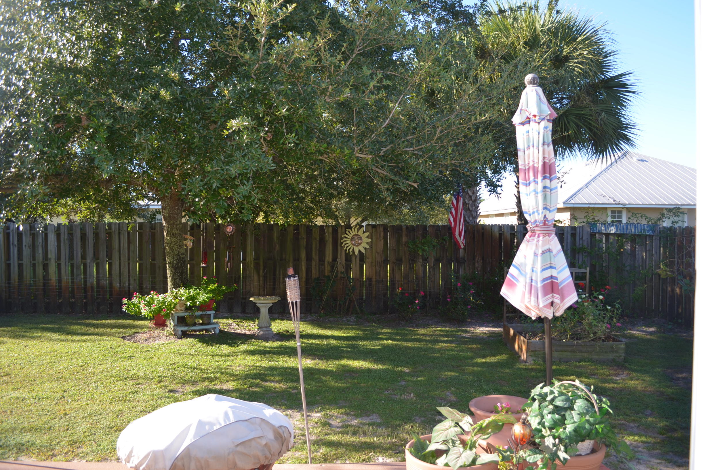 669 East Shipwreck Road Santa Rosa Beach, FL 32459 - Photo 25 of 35 a backyard of a house with table and chairs plants and large trees