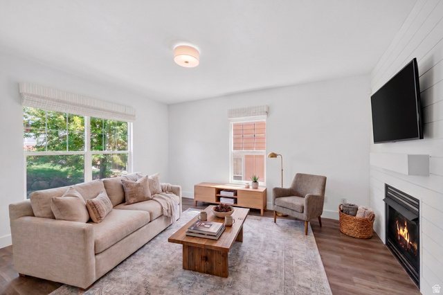 14771 Haddington Road Draper, UT 84020 - Photo 5 of 44 Living area featuring a shiplap accent wall with a built-in fireplace, wood-finish flooring, and large windows with privacy blinds