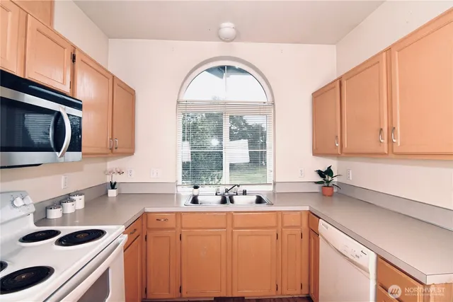 a kitchen with stainless steel appliances a sink a stove cabinets and a window
