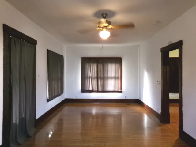 a view of an empty room with wooden floor and a window