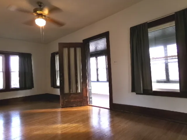 a view of an empty room with wooden floor and a window