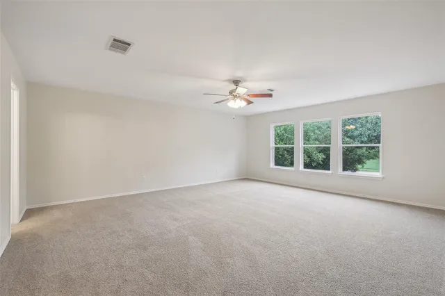 an empty room with windows and chandelier fan