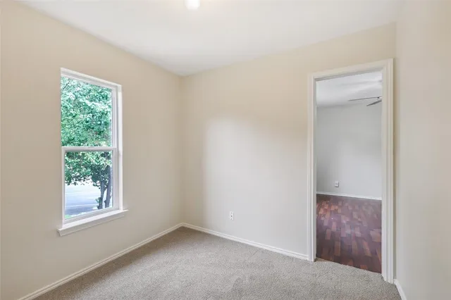 an empty room with a window and a fan