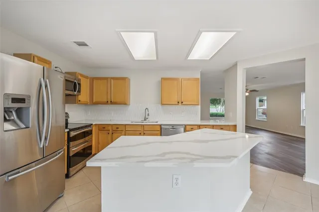 a room with stainless steel appliances a refrigerator a stove a microwave and cabinets