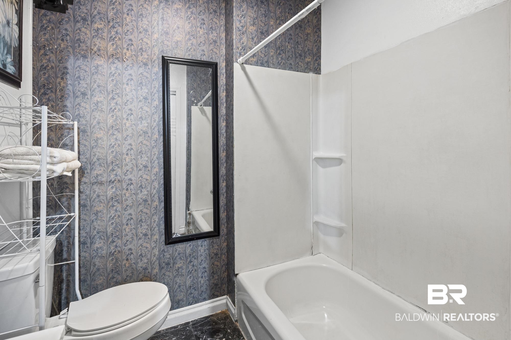 160 Glenn Avenue Mobile, AL 36606 - Photo 11 of 15 Bathroom featuring a white tub, shower surround, toilet, and a framed mirror
