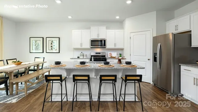 a kitchen with stainless steel appliances a stove a refrigerator a sink a dining table and chairs