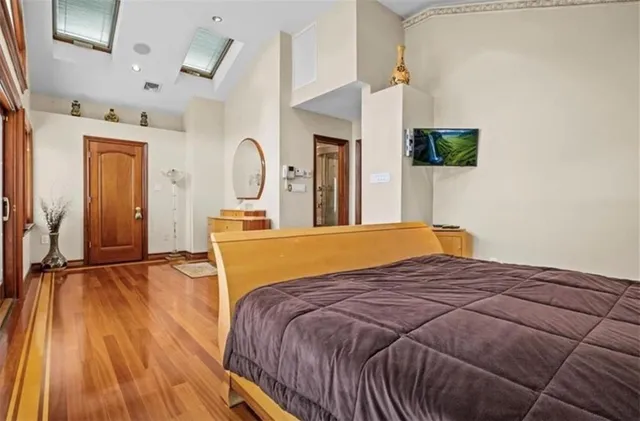 a bedroom with a bed and a flat tv screen on dresser