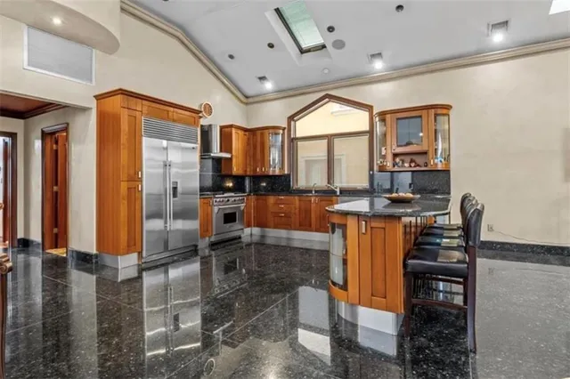 a kitchen with stainless steel appliances kitchen island granite countertop a refrigerator and a stove