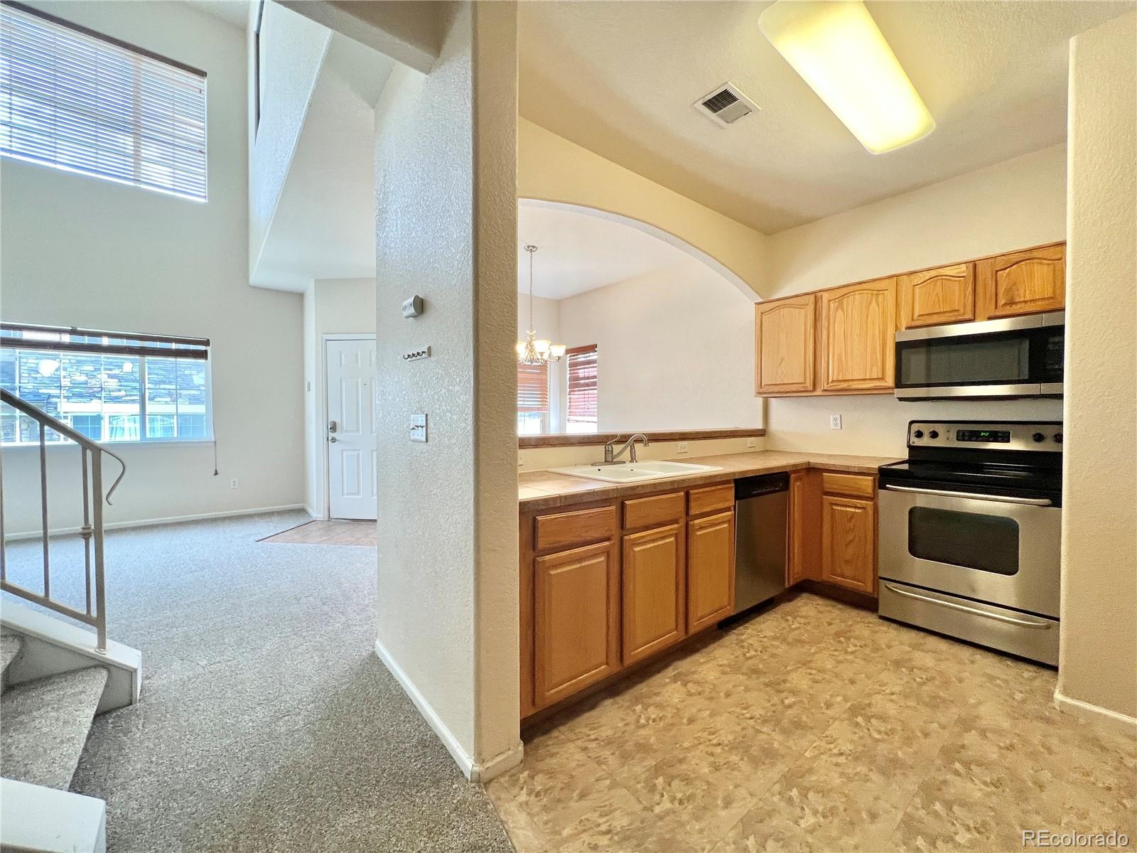 1385 South Chambers Road, Unit 102 Aurora, CO 80017 - Photo 4 of 20 a kitchen with stainless steel appliances granite countertop a stove a sink and a refrigerator
