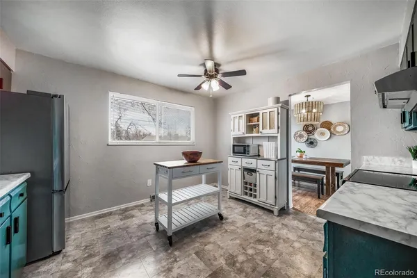 a living room with stainless steel appliances furniture a chandelier and a kitchen view