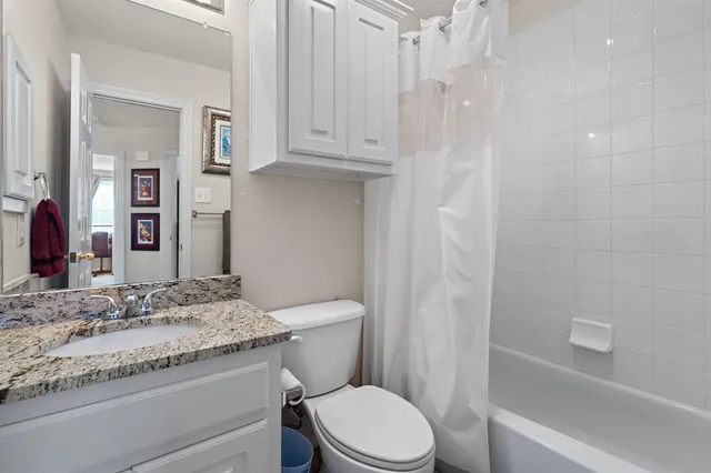 a bathroom with a granite countertop sink a toilet a mirror and shower