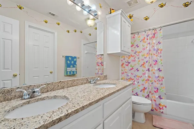 a bathroom with a granite countertop sink a mirror a toilet and shower curtain