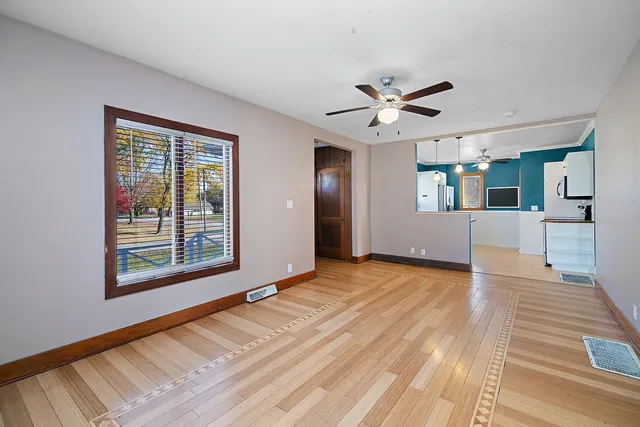 a view of an empty room with a window and wooden floor