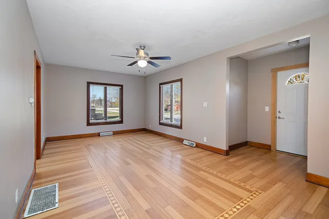 a view of an empty room with window and wooden floor