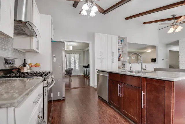 a kitchen with stainless steel appliances a sink stove and wooden floor
