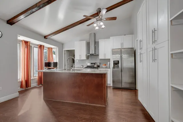 a kitchen with stainless steel appliances granite countertop a refrigerator a sink dishwasher a stove and a refrigerator with wooden floor