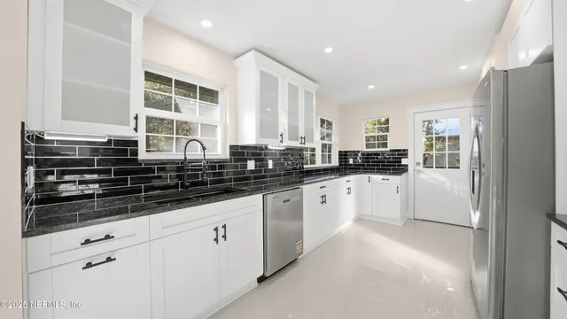 a kitchen with white cabinets and a window