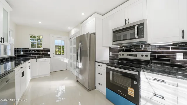 a kitchen with granite countertop a sink and white cabinets
