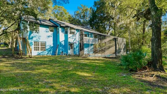 a front view of a house with a yard outdoor seating and covered with trees