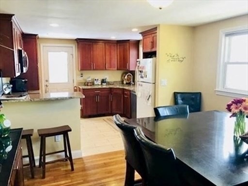 116 Upton Road Waltham, MA 02452 - Photo 9 of 15 a kitchen with stainless steel appliances granite countertop a stove top oven a sink a dining table and chairs with wooden floor