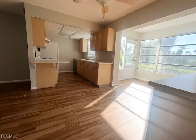 a large white kitchen with wooden floors and white stainless steel appliances