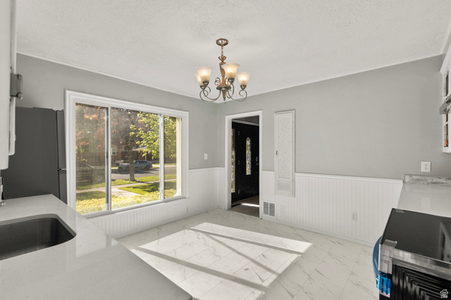 658 North 100 East Logan, UT 84321 - Photo 8 of 26 Bright dining area featuring a chandelier, large picture window, white beadboard wainscoting, and white tile flooring