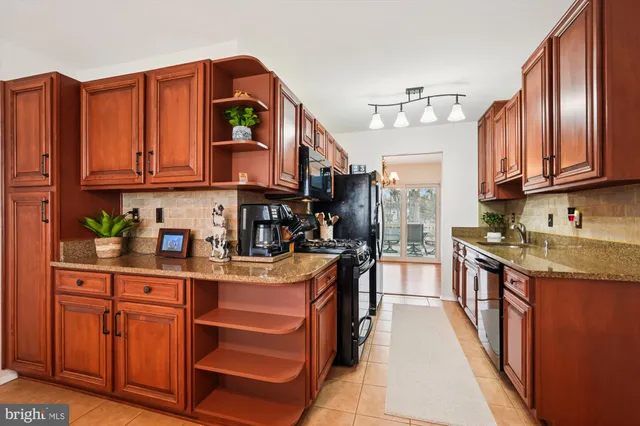 a kitchen with stainless steel appliances granite countertop a stove a sink dishwasher and cabinets with wooden floor