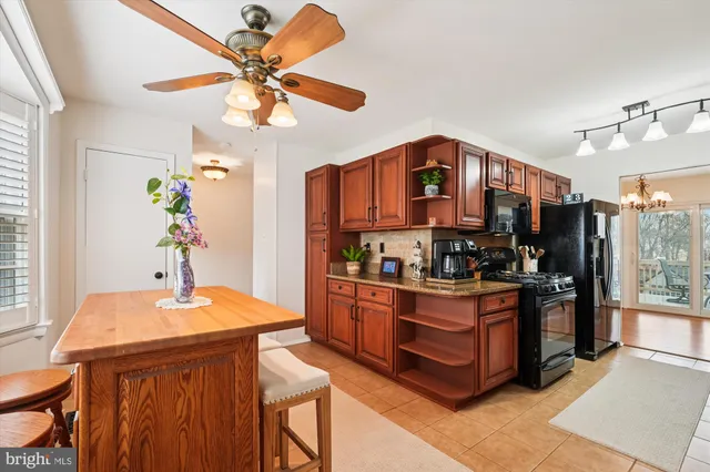 a kitchen with stainless steel appliances granite countertop a stove a refrigerator a sink a dining table and chairs with wooden floor