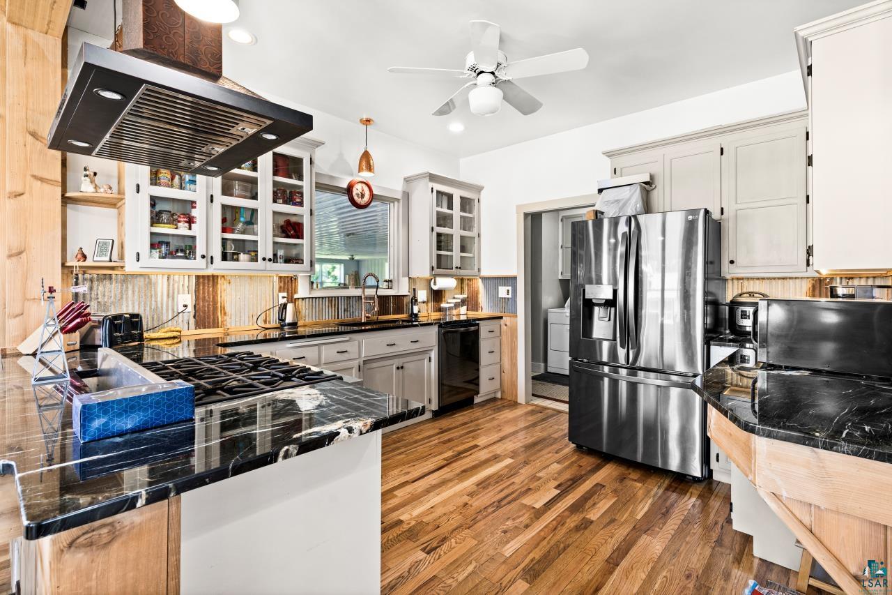 33415 Jackson Road Askov, MN 55704 - Photo 38 of 91 Kitchen featuring stainless steel refrigerator with ice dispenser, wood finished floors, a ceiling fan, range hood, and glass insert cabinets