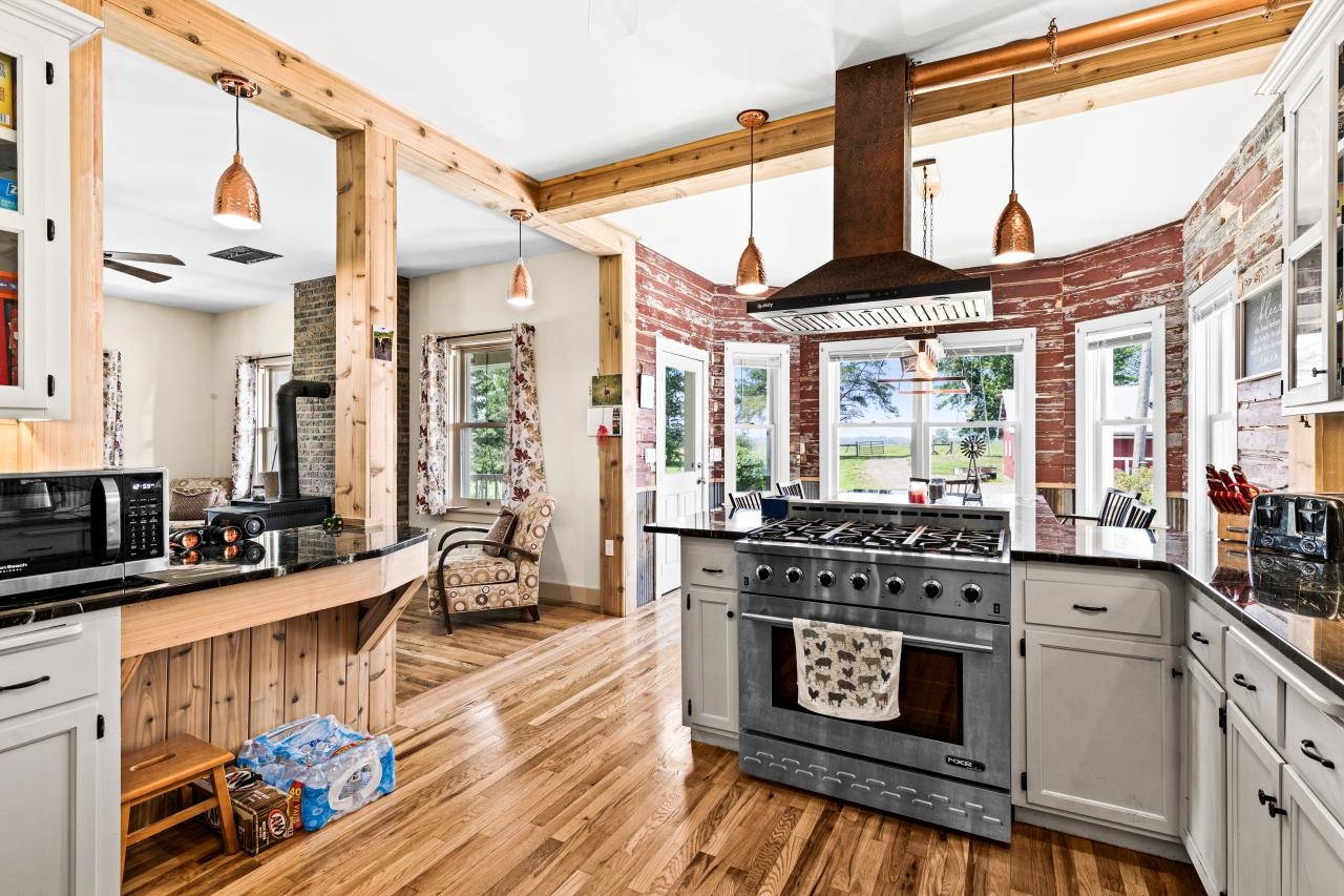 33415 Jackson Road Askov, MN 55704 - Photo 40 of 91 Kitchen featuring dark countertops, appliances with stainless steel finishes, island exhaust hood, light wood finished floors, and a peninsula