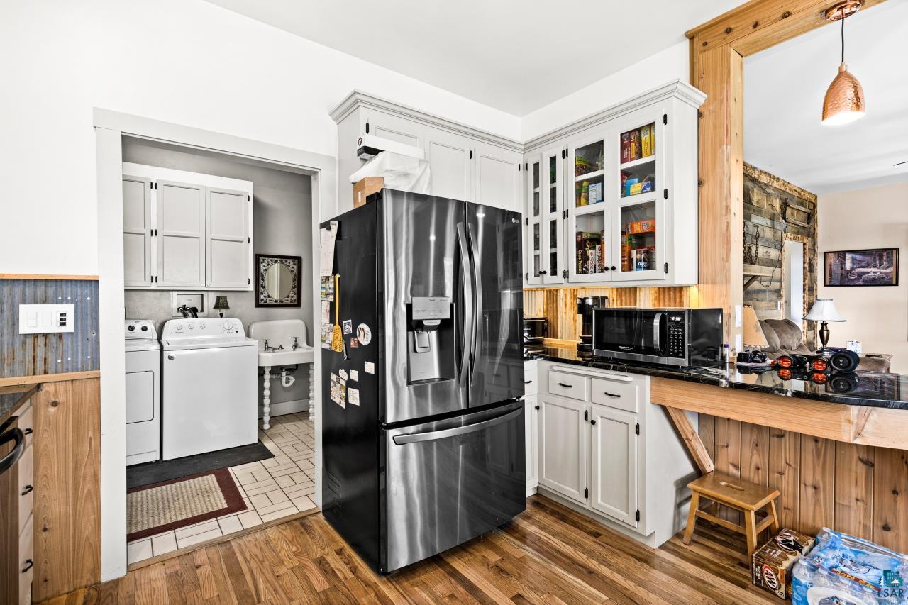 33415 Jackson Road Askov, MN 55704 - Photo 41 of 91 Kitchen featuring washer and dryer, stainless steel fridge, glass insert cabinets, dark countertops, and white cabinetry