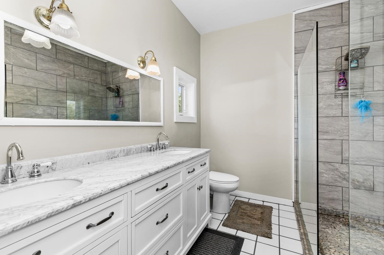 33415 Jackson Road Askov, MN 55704 - Photo 55 of 91 Full bathroom featuring double vanity, tiled shower, and tile patterned flooring