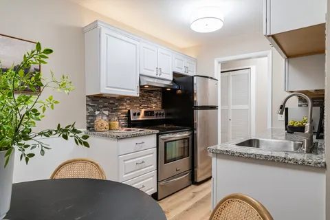 a kitchen with stainless steel appliances granite countertop a stove a sink and a refrigerator