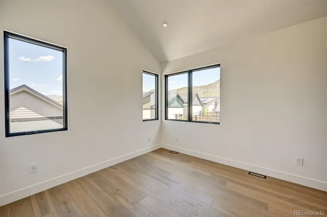 a view of a hallway with wooden floor and a bathroom
