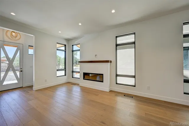 an empty room with wooden floor fireplace and windows