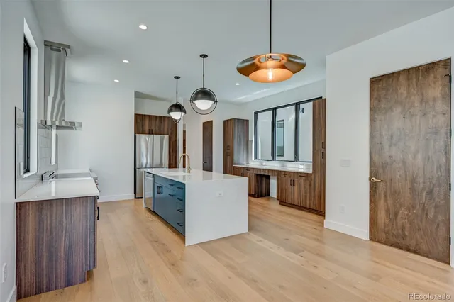 a large kitchen with stainless steel appliances a large counter top a stove and a sink